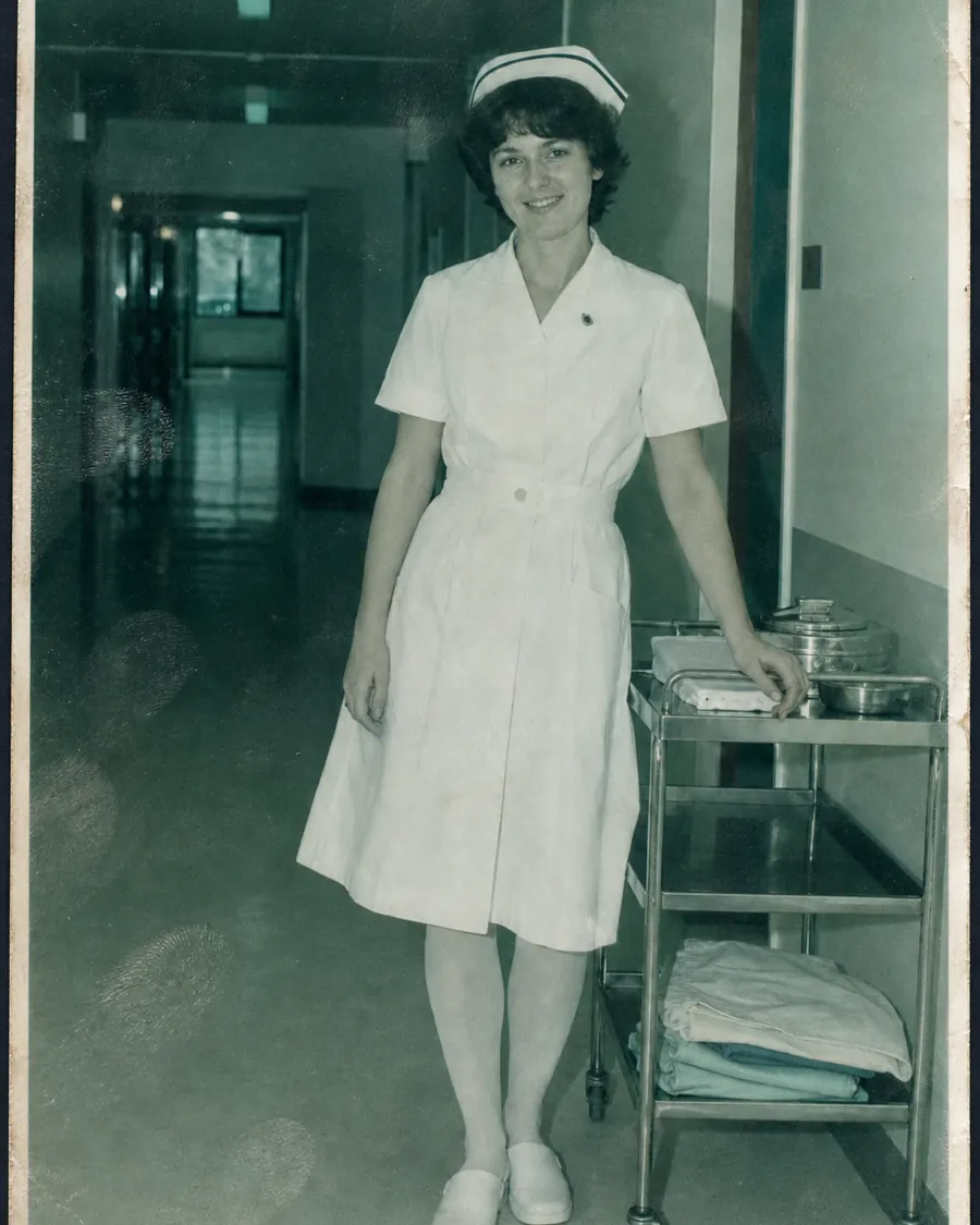 Foto uit 1983: een verpleegkundige van drieëntwintig in uniform op een ziekenhuisgang, de afdruk groen verkleurd en vingerafdrukken over het oppervlak.
