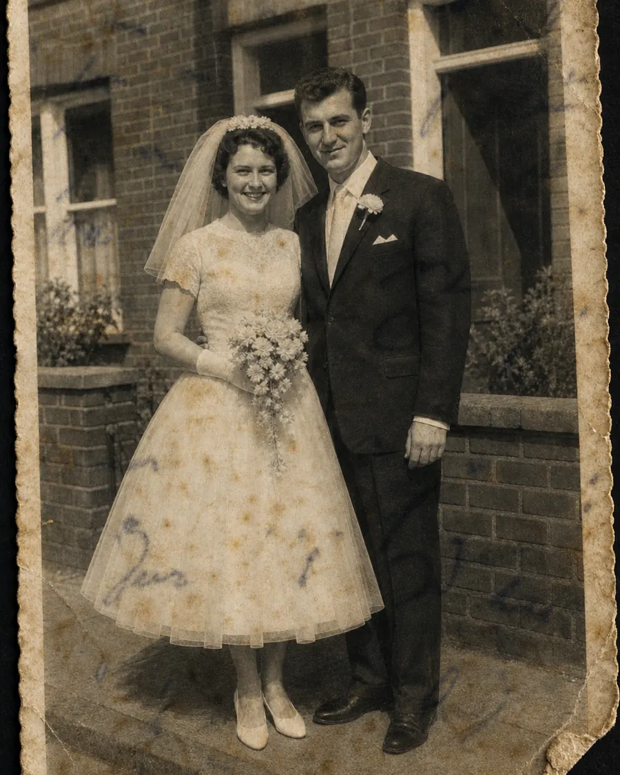 Trouwfoto uit 1961: het paar voor een bakstenen huis, zij met een boeket; over de hele afdruk staan bruine vlekken en iemand heeft er met pen overheen geschreven.
