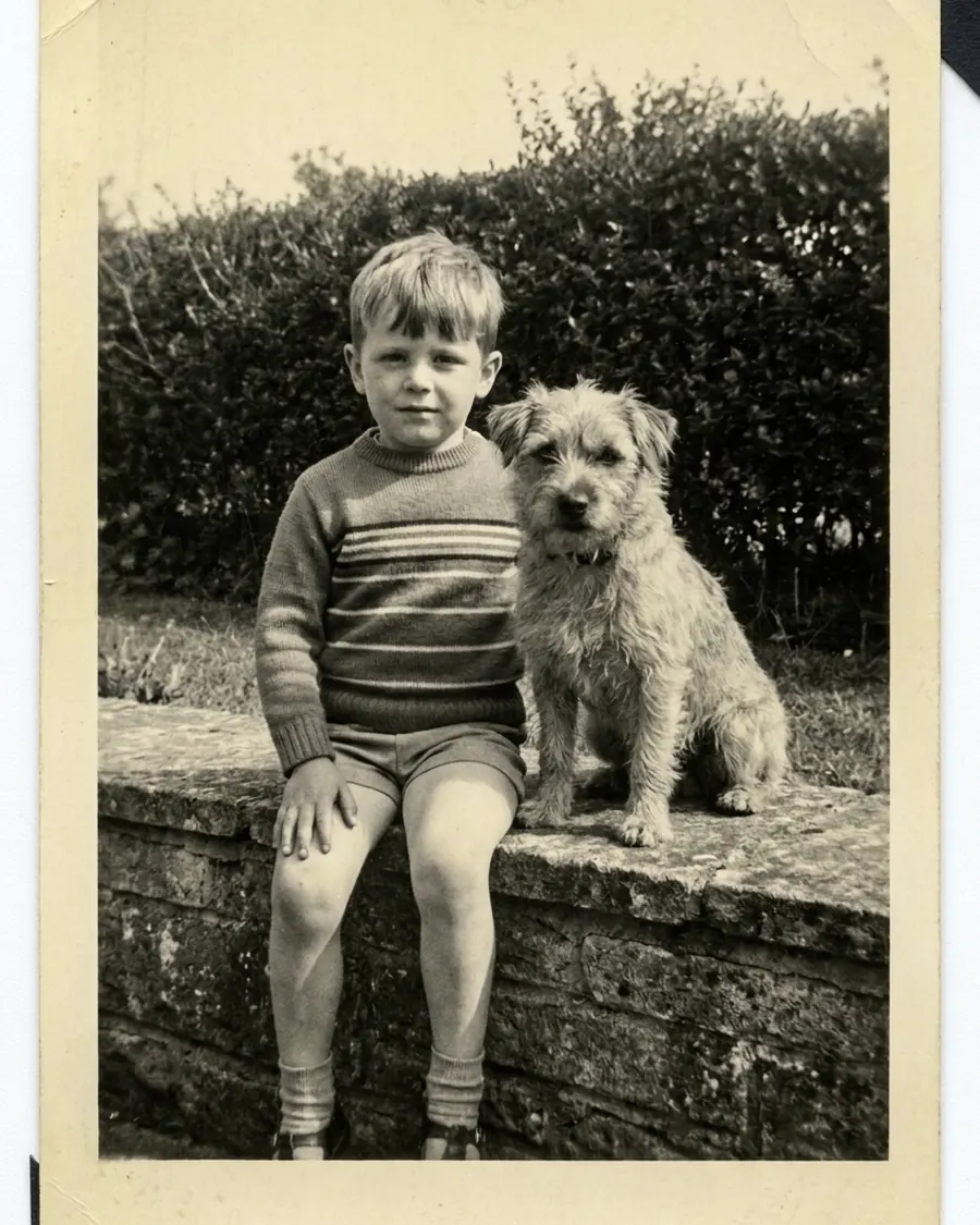 Kinderfoto uit 1967: een jongen in een gestreepte trui naast een ruwharige hond op een muurtje; de zwart-witafdruk is vergeeld en de randen zijn beschadigd.